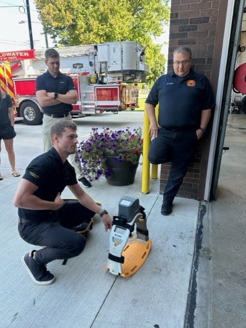 Fireman Ryan Barle looks on while representatives of the manufacturer show the Lucas CPR machine.