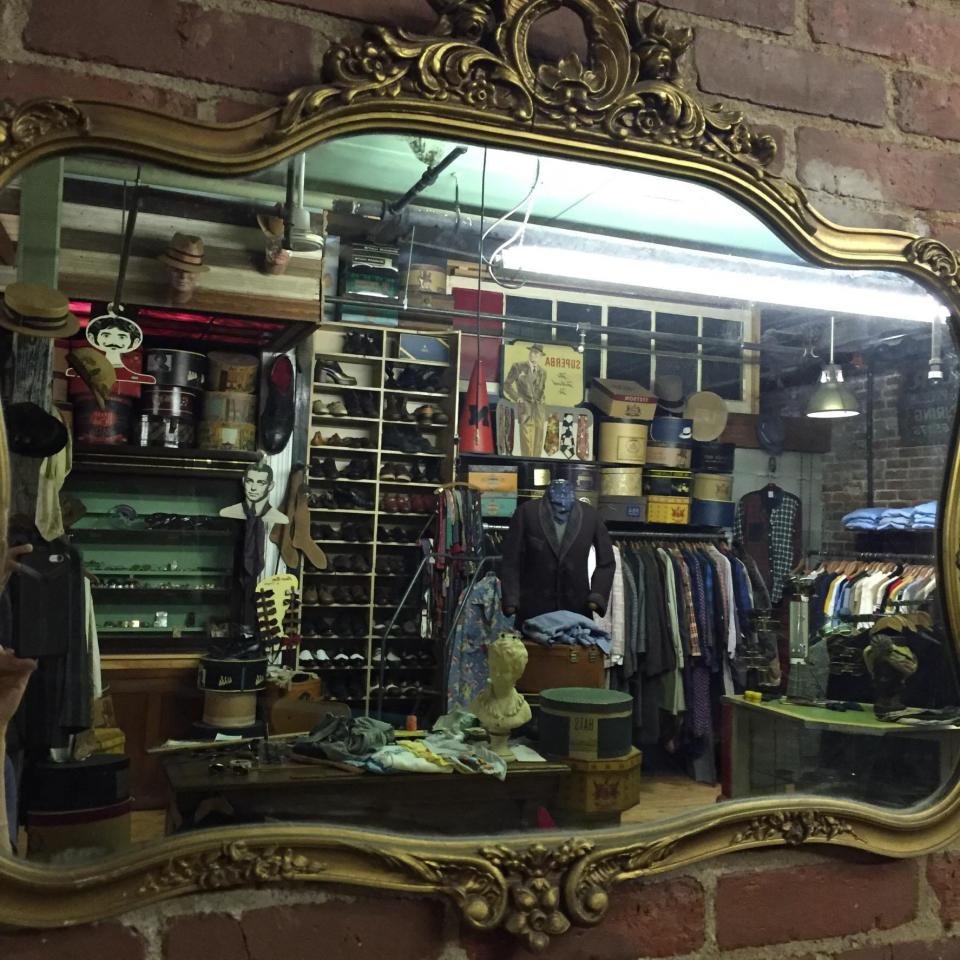 The view through an antique mirror shows some of the men's formal wear at Circa Vintage Clothing.