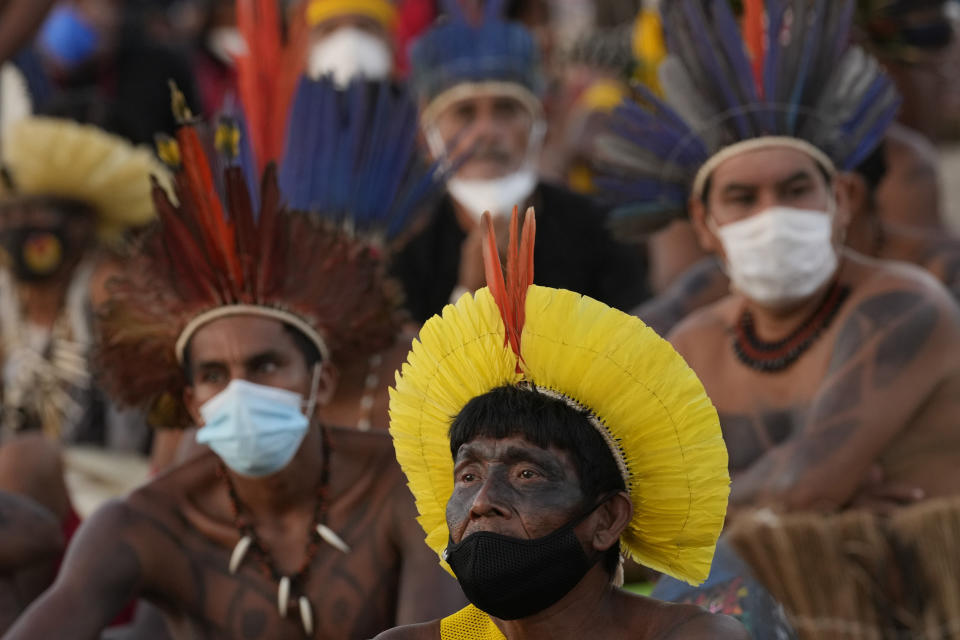 Indigenous people watch a Supreme Court session on a TV screen, that is expected to issue a ruling that will have far-reaching implications for tribal land rights, outside the Supreme Court building, in Brasilia, Brazil, Wednesday, Aug. 25, 2021. (AP Photo/Eraldo Peres)