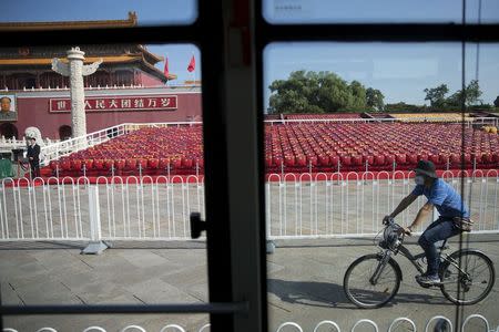 A man cycles past stands raised at Beijing's Tiananmen Square September 2, 2015 as the capital prepares for Wednesday's parade. REUTERS/Damir Sagolj