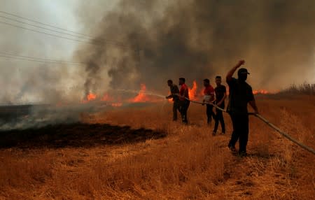 Iraqi farmers and other residents attempt to put out a fire that engulfed a wheat field in the northern town of Bashiqa, east of Mosul