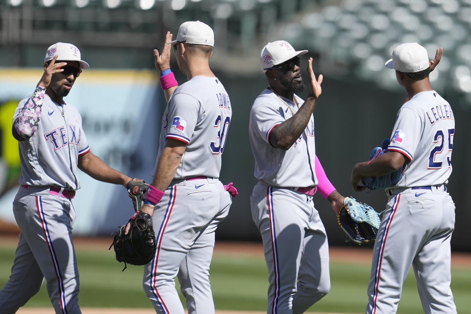 Texas Rangers' Marcus Semien, from left, celebrates with Nathaniel Lowe, Adolis Garcia and Jose Leclerc after defeating the Oakland Athletics in a baseball game in Oakland, Calif., Sunday, May 14, 2023. (AP Photo/Jeff Chiu)