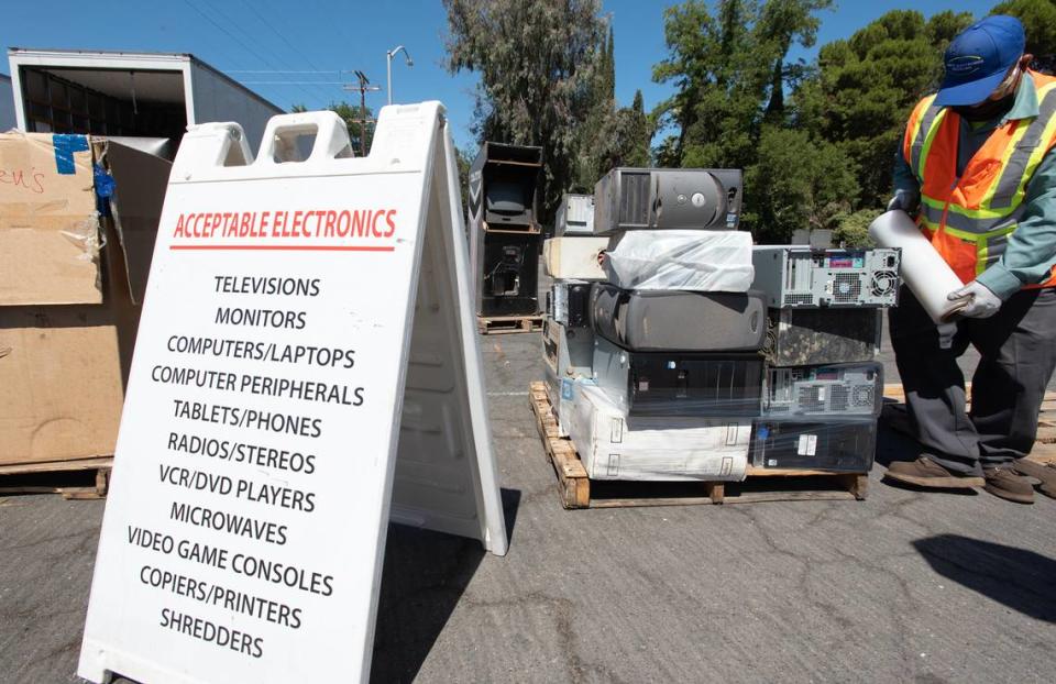 Onsite Electronic Recycling worker Rolando Ibarra wraps up a pallet of junked computers during a Modesto city sponsored trash day at John Thurman Field in Modesto, Calif., on Saturday, June, 25, 2022.