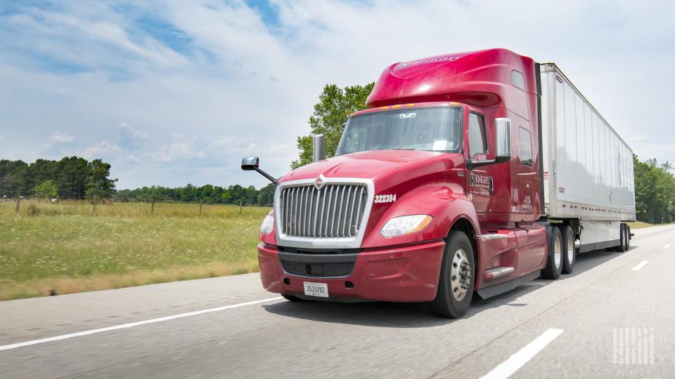 A maroon Knight tractor pulling a white Knight trailer on a highway