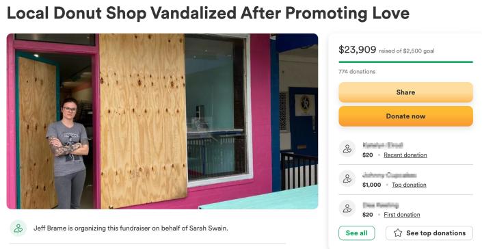 woman stands with arms crossed in front of boarded-up window and door