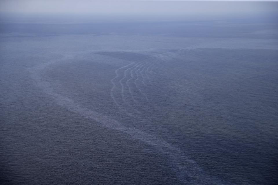 FILE - This March 31, 2015, aerial file photo, shows an oil sheen drifting from the site of the former Taylor Energy oil rig in the Gulf of Mexico, off the coast of Louisiana. A new federally led estimate of oil seeping from a platform toppled off Louisiana 14½ years ago is below other recent estimates. But the report contradicts the well owner’s assertions about the amount and source of oil. Oil and gas have been leaking into the Gulf of Mexico since a subsea mudslide caused by Hurricane Ivan on Sept. 15, 2004 knocked over a Taylor Energy Co. production platform. (AP Photo/Gerald Herbert, File)