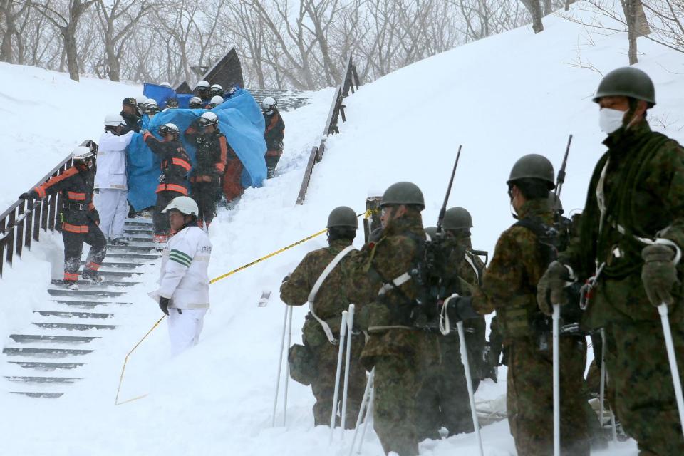 Rescue operation: Firefighters carry a survivor from the site of the avalanche: AFP/Getty Images