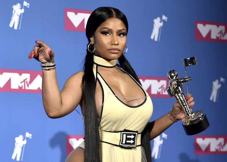 A woman with long black hair in pigtails holding a silver moon man trophy