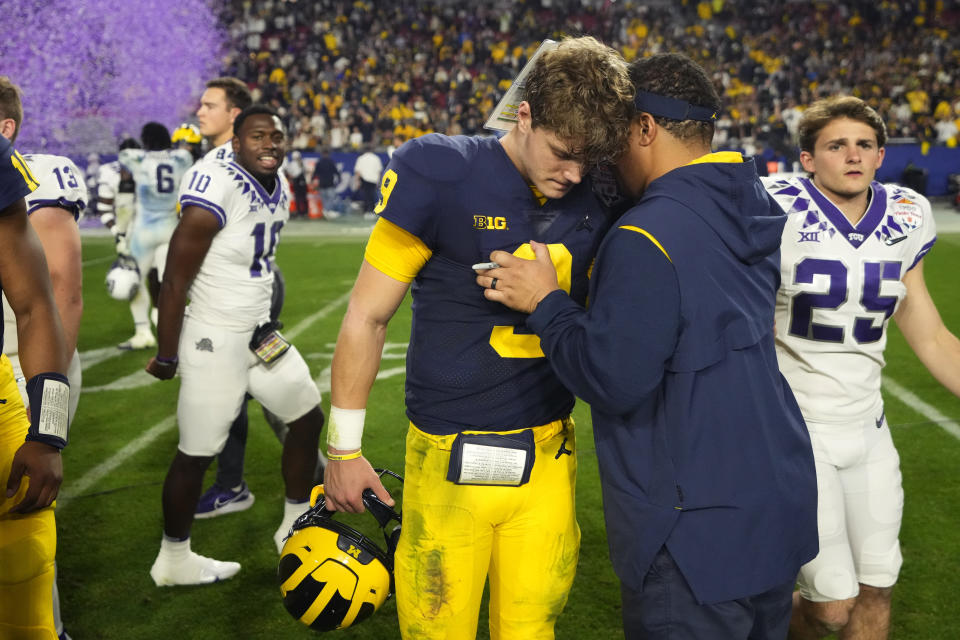 Michigan quarterback J.J. McCarthy (9) embraces a coach after the Fiesta Bowl NCAA college football semifinal playoff game against TCU, Saturday, Dec. 31, 2022, in Glendale, Ariz. TCU defeated Michigan 51-45. (AP Photo/Ross D. Franklin)