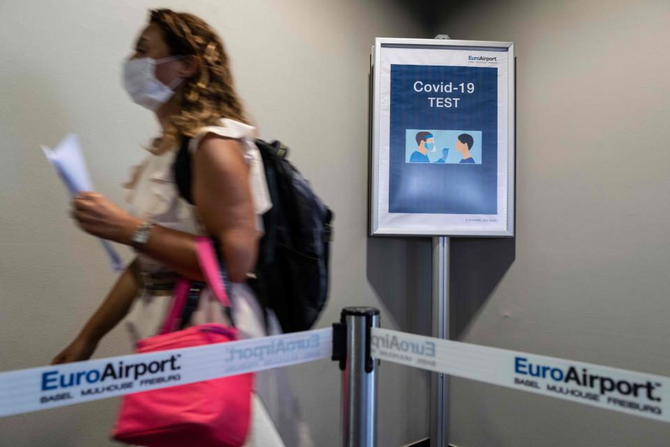 A passenger arriving from Istanbul and wearing a face mask, walks past a COVID-19 (novel coronavirus) test sign at the arrival hall of the Basel - Mulhouse Euroairport in Saint Louis, eastern France, on August 4, 2020. (Photo by SEBASTIEN BOZON / AFP) (Photo by SEBASTIEN BOZON/AFP via Getty Images)