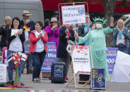 A woman dressed as New York's Statue of Liberty attends a demonstration of the tourism business at the cathedral square in Erfurt, Germany, Wednesday, May 20, 2020. Representatives of coach companies, travel agencies and tour operators protest to draw attention to the difficult situation caused by the ban on employment since the new coronavirus outbreak. Slogen on her protest poster reads: 'Tourism keeps the world together'. (AP Photo/Jens Meyer)