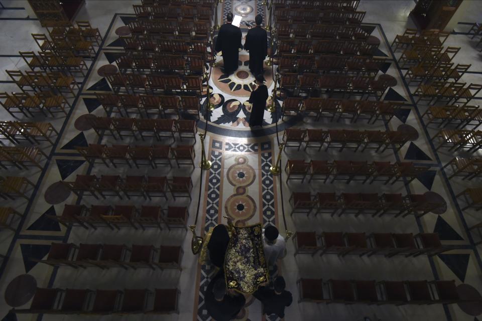 Greek Orthodox priests hold aloft the bier depicting Christ's preparation for burial during the Good Friday procession of the Epitaphios, held without worshippers inside an empty church in the northern city of Thessaloniki, Greece, during a lockdown order by the government to prevent the spread of coronavirus, Friday, April 17, 2020. Greek authorities are tightening lockdown enforcement during the Holy Week ahead of Orthodox Easter, when Greeks traditionally flock to rural family homes for the most popular event on the country's religious calendar. Easter celebrations will be drastically scaled down, with church services held behind closed doors, even on April 19, Easter Day. (AP Photo/Giannis Papanikos)