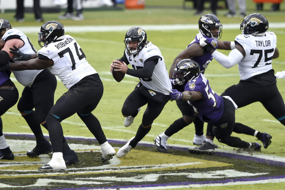 Jacksonville Jaguars quarterback Gardner Minshew II, center left, runs with the ball while Baltimore Ravens linebacker Tyus Bowser (54) tries to stop him during the first half of an NFL football game, Sunday, Dec. 20, 2020, in Baltimore. (AP Photo/Gail Burton)