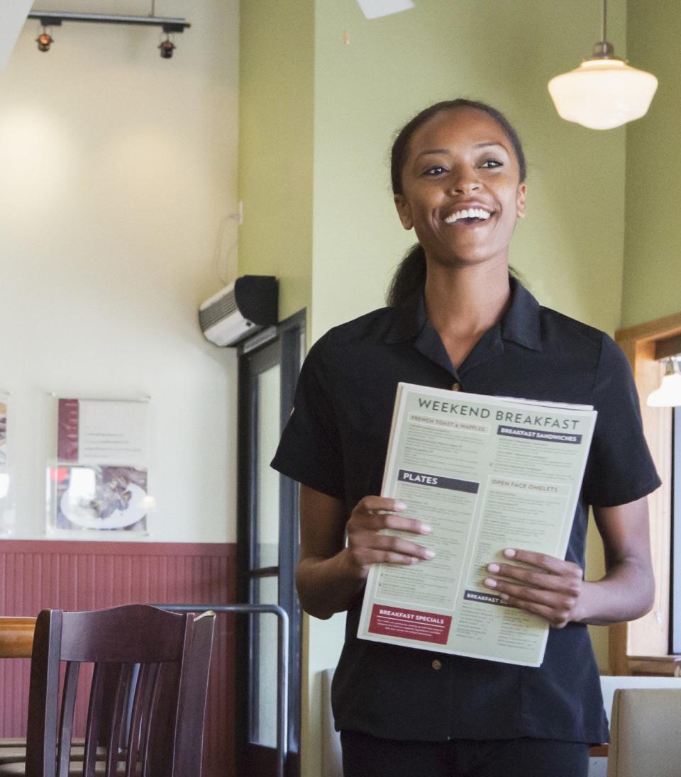 a woman smiling and holding menus