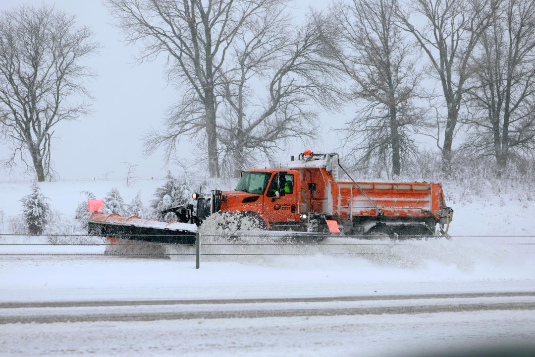 A plow clears snow on a highway.