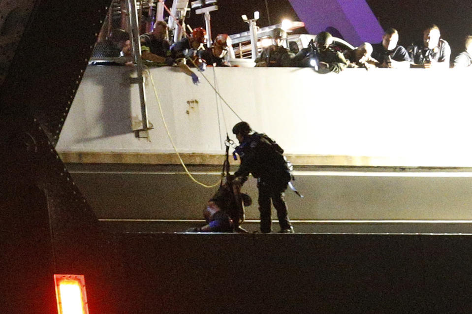 Sylvester Holt, left, is rescued by an officer Friday, Jan. 20, 2017, in New Orleans. Holt was wanted in the connection with the shooting of his wife and a Westwego police officer. (AP Photo/Jonathan Bachman)