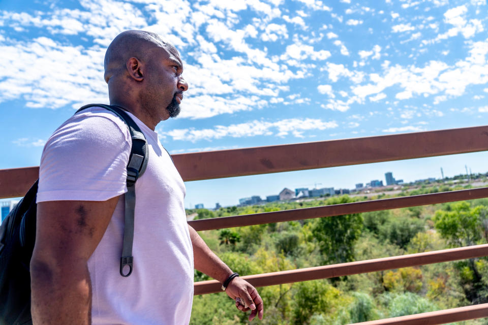 Jesston Williams, a board member and community organizer for Fund for Empowerment, walks across a bridge overlooking the Rio Salado riverbed in Tempe on Aug. 31, 2022. Tempe gave notice for people living in the river bottom to vacate by Aug. 31.
