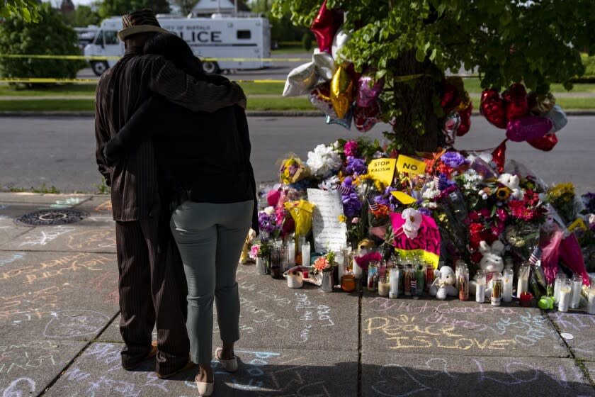 Anthony Marshall comforts Shannon Waedell-Collins, after Waedell-Collins placed flowers at a makeshift memorial