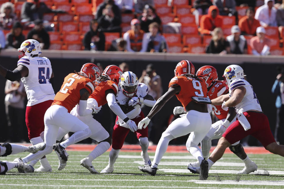 Kansas's Devin Neal (4) is tackled by Oklahoma State's Kendal Daniels (5), Korie Black (2), Trey Rucker (9) and Collin Clay (93) during the first quarter of an NCAA college football game in Stillwater, Okla., Saturday, Oct. 14, 2023. (AP Photo/Mitch Alcala)