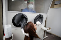 A healthcare worker takes a nasal swab sample for a for COVID-19 test from inside a freestanding isolation booth at a hospital in Buenos Aires, Argentina, Monday, Oct. 19, 2020. (AP Photo/Natacha Pisarenko)