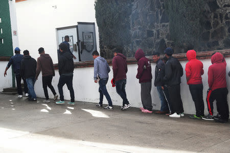 Migrants from the a caravan of thousands from Central America trying to reach the United States wait in line to be voluntarily sent back to their countries of origin at Mexico's National Immigration Institute in Tijuana, Mexico, January 18, 2019. REUTERS/Shannon Stapleton