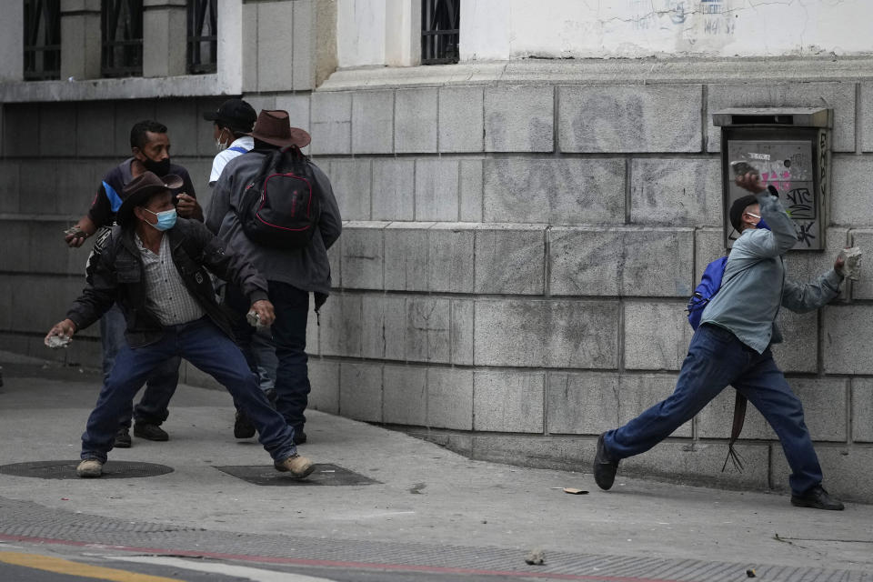 Protesters throw stones at police during a protest of veterans demanding that a law be passed that compensates them for having served during the country's civil war, outside the Congress building in Guatemala City, Tuesday, Oct. 19, 2021. (AP Photo/Moises Castillo)