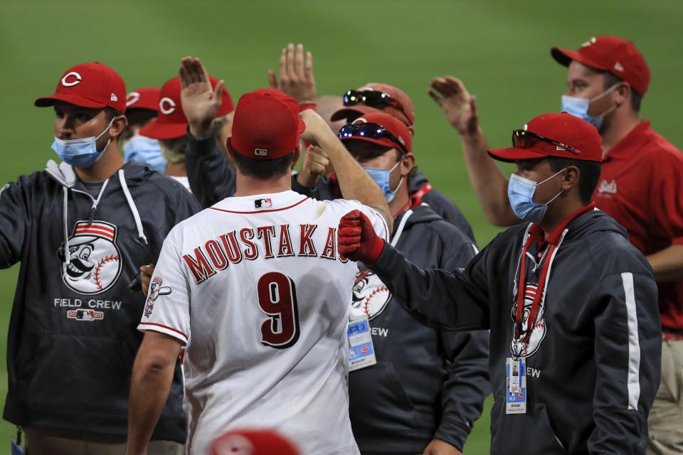 Cincinnati Reds' Mike Moustakas fist bumps members of the Reds' grounds crew after a baseball game against the Milwaukee Brewers in Cincinnati, Wednesday, Sept. 23, 2020. The Reds won 6-1. (AP Photo/Aaron Doster)