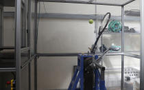 In this photo taken Friday June, 28, 2019, a serve-simulating robot arm nicknamed "Myo," from the Greek word for "muscle" is about to hit a ball dropped from above at the International Tennis Federation (ITF) lab in Roehampton, near Wimbledon south west London. Based for about 20 years in a three-room area on what used to be a pair of squash courts in Roehampton, the ITF tech lab is filled with more than $1 million worth of machines that help make sure rules are followed and parameters are met. (AP Photo/Alastair Grant)