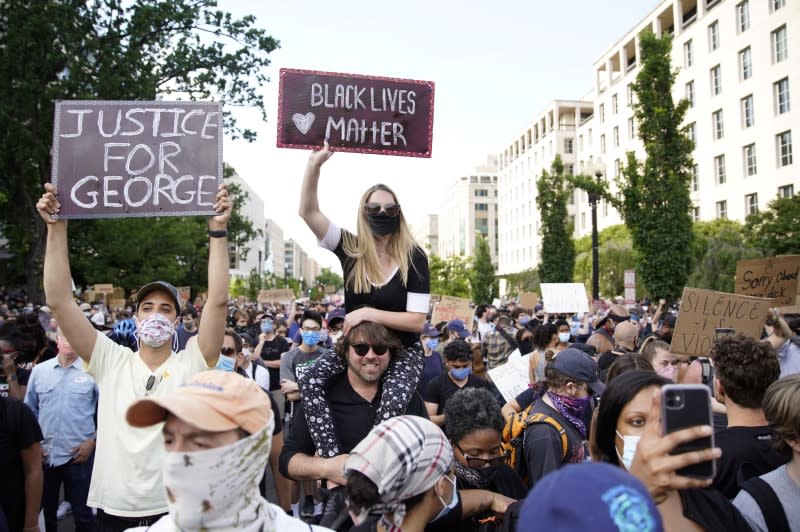 Manifestantes sotienen carteles durante una protesta contra la muerte de George Floyd, un afroamericano que estaba bajo custodia policial en Mineápolis, en Washington, EEUU