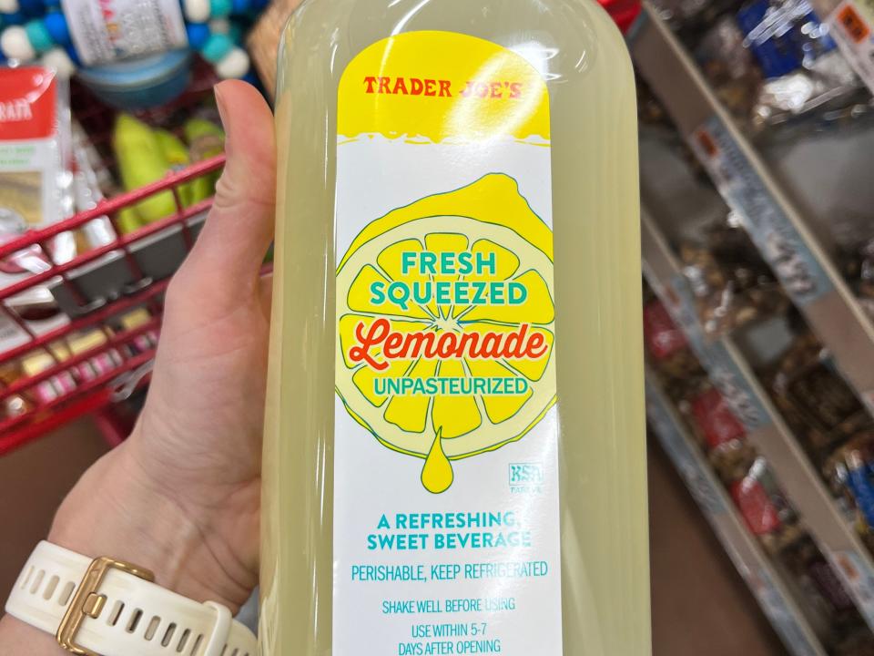 A hand holding a bottle of Trader Joe's fresh-squeezed lemonade.