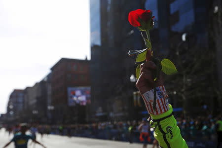 A runner holds up a rose as she finish the 120th running of the Boston Marathon in Boston, Massachusetts April 18, 2016. REUTERS/Brian Snyder