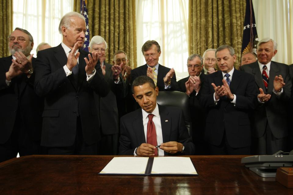 FILE - In this Jan. 22, 2009, file photo, President Barack Obama caps his pen after he signed an executive order closing the prison at Guantanamo Bay in the Oval Office of the White House in Washington. Vice President Joe Biden, second from left, and retired military officers applaud. (AP Photo/Charles Dharapak, File)