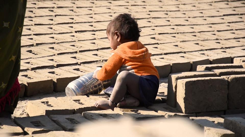 Child sitting amongst clay bricks on brick kilns