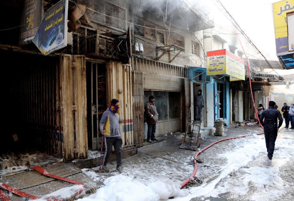 Civilians inspect the site after a parked car bomb went off at a commercial center in Khilani Square in central Baghdad, Iraq, Wednesday, Feb. 5, 2014. Multiple bombings rocked central Baghdad on Wednesday, striking mainly near the heavily fortified Green Zone where key government offices are located and killing at least 16 people, Iraqi officials said. (AP Photo/Karim Kadim)