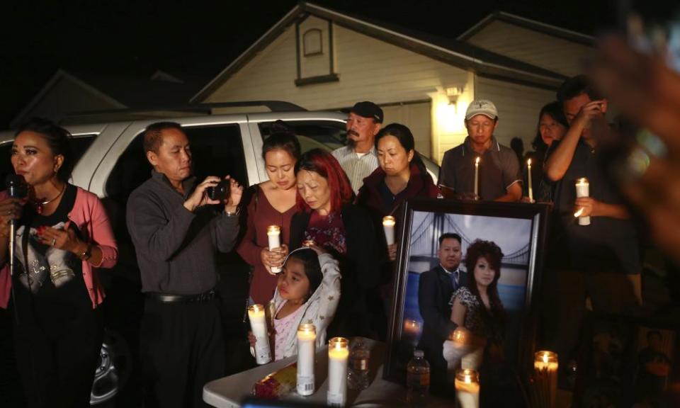 The wife and daughter of shooting victim Kou Xiong stand during the candle light vigil in his honor outside their home in Fresno, California.