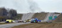 Smoke rises in the distance as firefighters block a highway leading to an area where a train derailed, in the small town of Gainford, Alberta west of Edmonton October 19, 2013. The train carrying crude oil and liquefied petroleum gas derailed west of Edmonton, Alberta, causing an explosion and fire but no injuries, Canadian National Railway said on Saturday. REUTERS/Dan Riedlhuber (CANADA - Tags: DISASTER TRANSPORT)