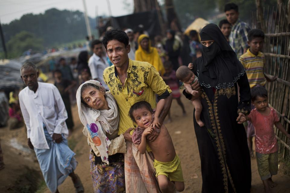 FILE - In this Sept. 5, 2017, file photo, an exhausted Rohingya helps an elderly family member and a child as they arrive at Kutupalong refugee camp after crossing from Myanmar to the Bangladesh side of the border, in Ukhia. There was a time when Suu Kyi was the hero of the human rights set, whose nonviolent struggle against her country's military dictatorship was admired by people around the world and won her the Nobel Peace Prize in 1991. Now she is seen by many of her admirers as an apologist for war crimes against its Muslim Rohingya minority. (AP Photo/Bernat Armangue, File)