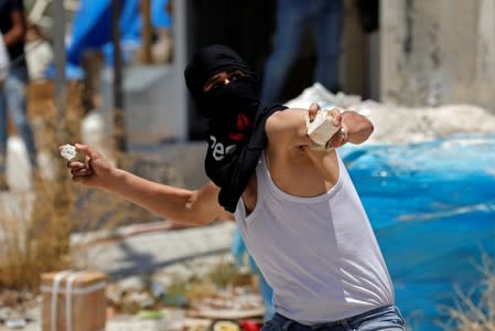 Palestinian demonstrator hurls stones at Israeli forces during a protest against Bahrain's workshop for U.S. peace plan, near Hebron, in the Israeli-occupied West Bank