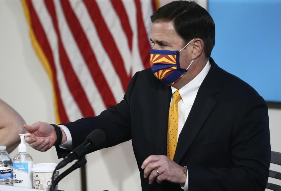 Arizona Republican Gov. Doug Ducey uses hand sanitizer as he wears a face covering prior to speaking about the latest coronavirus data at a news conference Thursday, June 25, 2020, in Phoenix. (AP Photo/Ross D. Franklin, Pool)