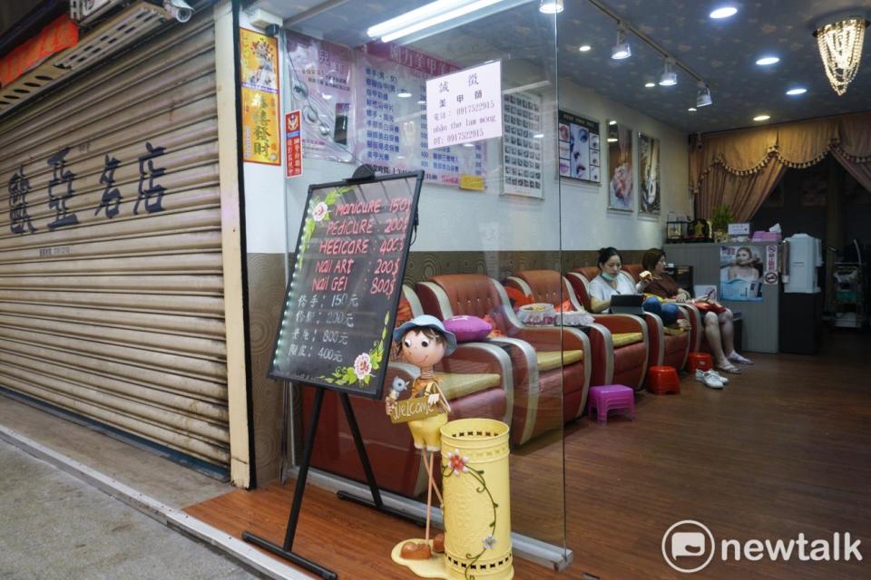 華西街觀光夜市的一家美甲店，由於沒有顧客上門，工作人員只好坐在椅子上滑手機看影片。   圖：張良一/攝