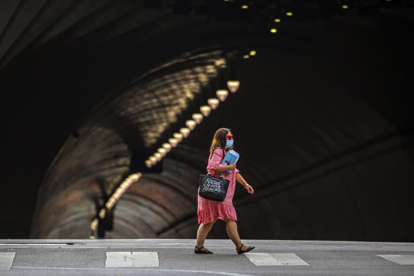 Los Angeles, CA - August 11: A lady in face mask crosses a street Wednesday, Aug. 11, 2021 in Los Angeles, CA. (Irfan Khan / Los Angeles Times)