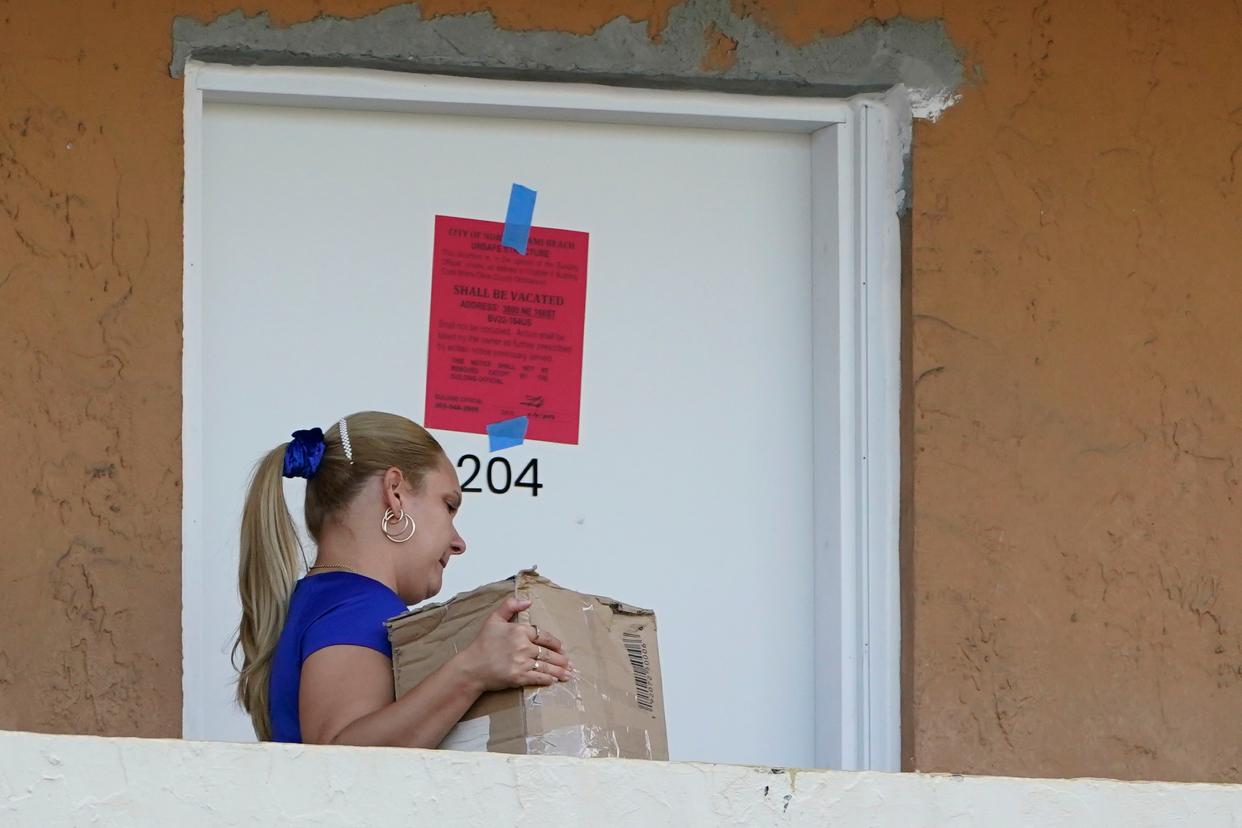 A woman takes belongings from an apartment at the Bayview 60 Homes apartment building, Tuesday, April 5, 2022, in North Miami Beach, Fla. 