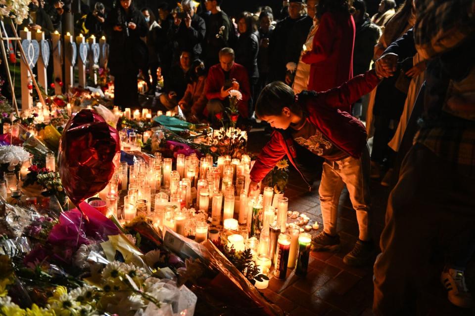 A young boy bends down toward a cluster of lighted candles.