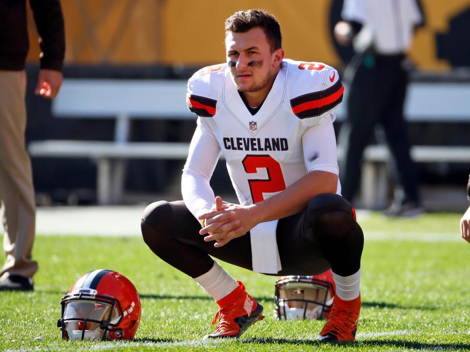Johnny Manziel squats on the field while competing for the Cleveland Browns.