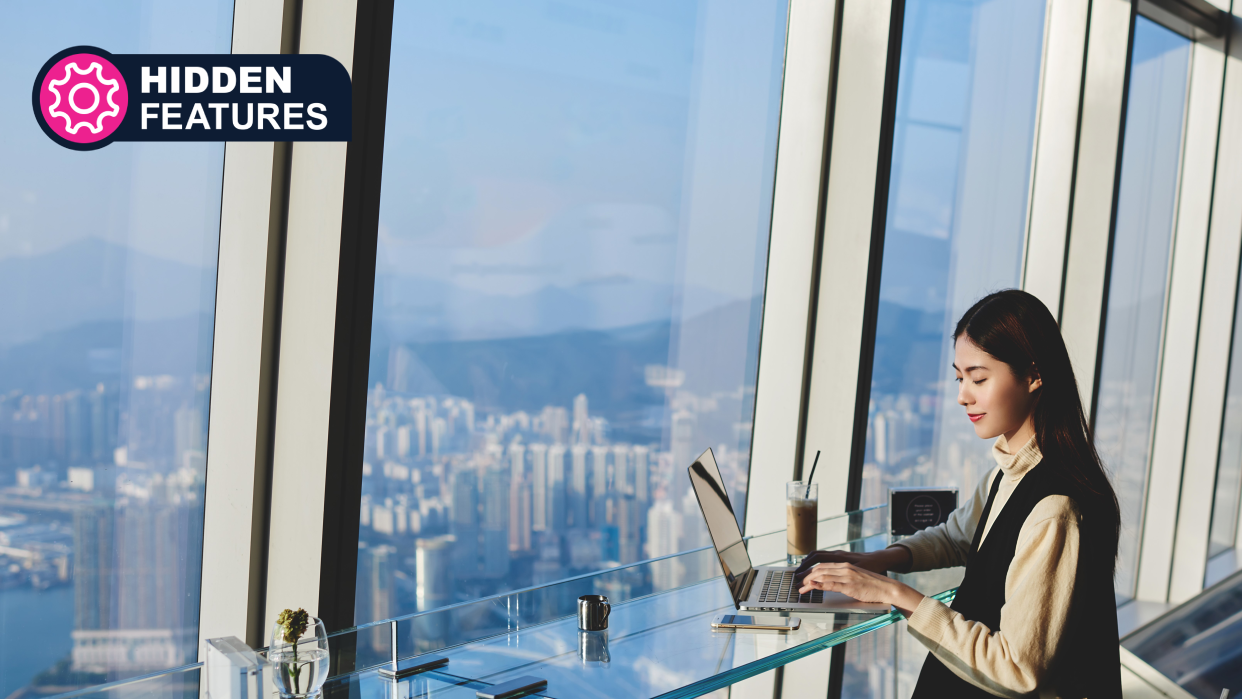  A woman is working on laptop computer  while sitting in coffee shop in skyscraper near window with view of metropolitan city. 