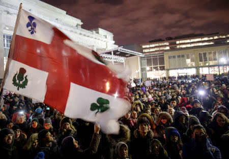 The flag of the city of Montreal flies over a crowd as people attend a vigil in support of the Muslim community in Montreal, Quebec, January 30, 2017. REUTERS/Dario Ayala