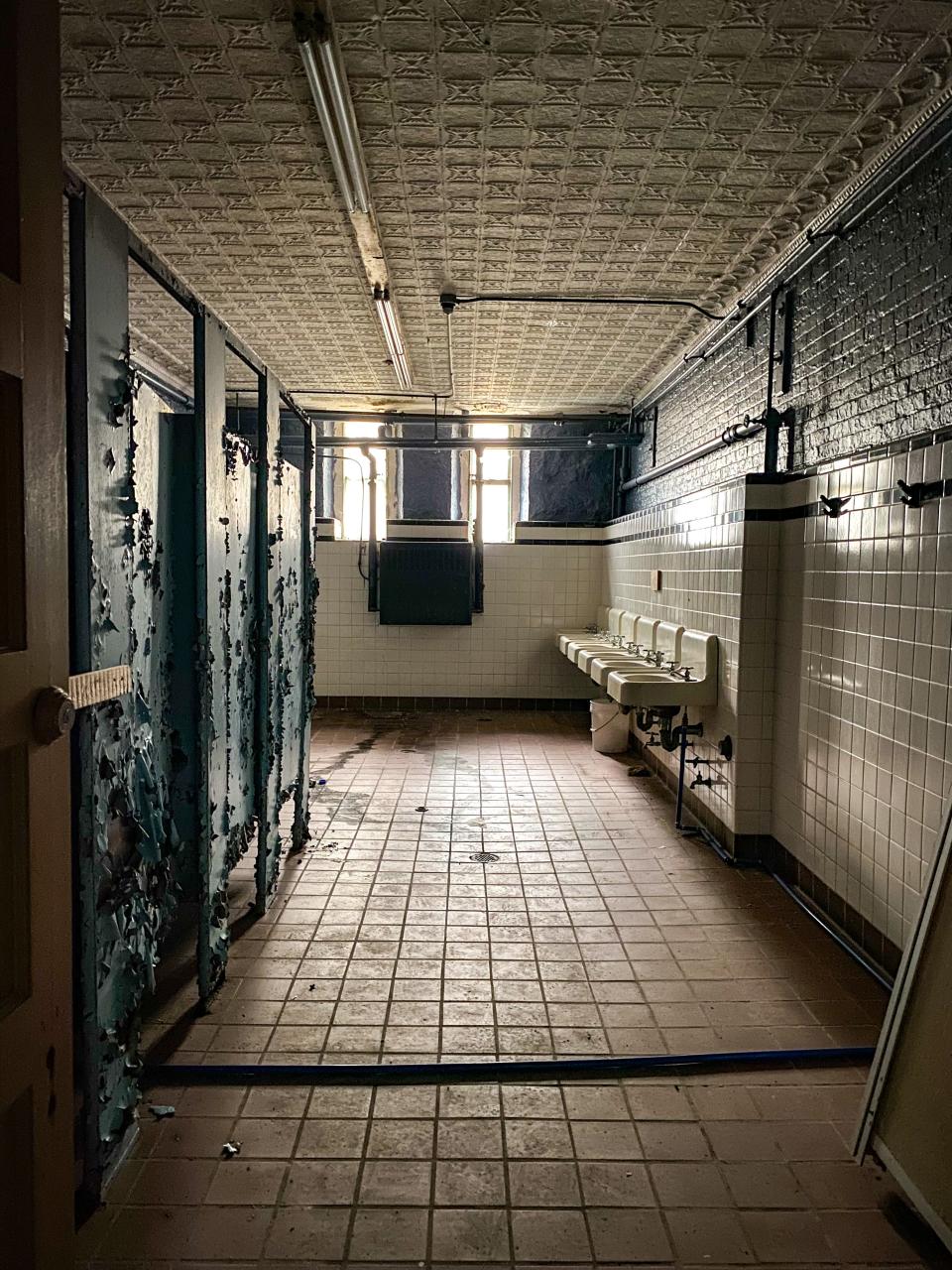 A bathroom, wrought in tile, brick and tin ceilings, has succumbed to decay in the basement of the Bank Street Armory in Fall River.