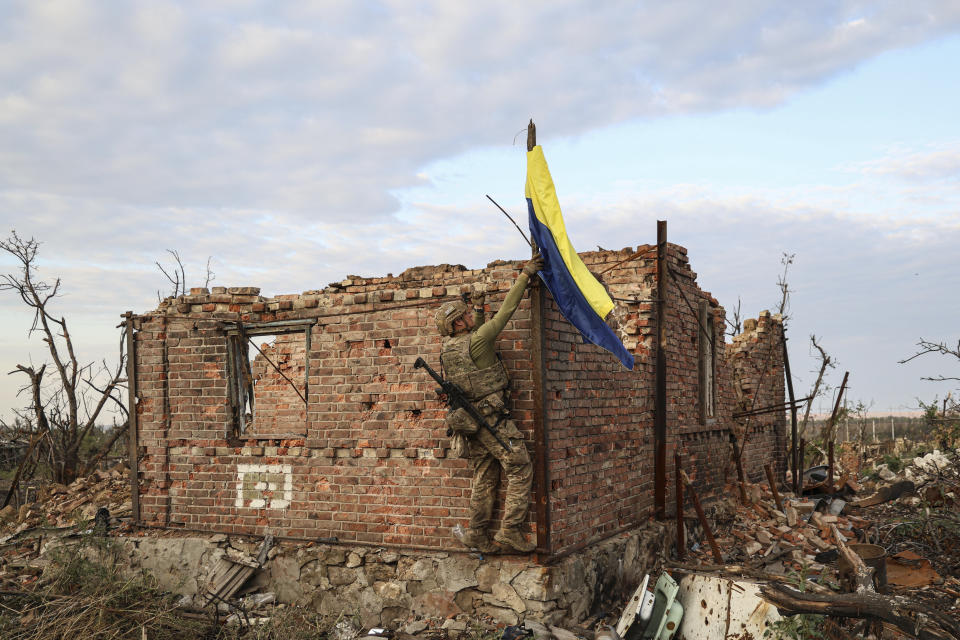 An assault unit commander raises the Ukrainian flag as a symbol of liberation of the frontline village of Andriivka, Ukraine, on Saturday.