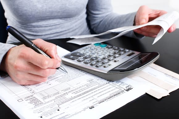 Person with calculator filling out a tax form