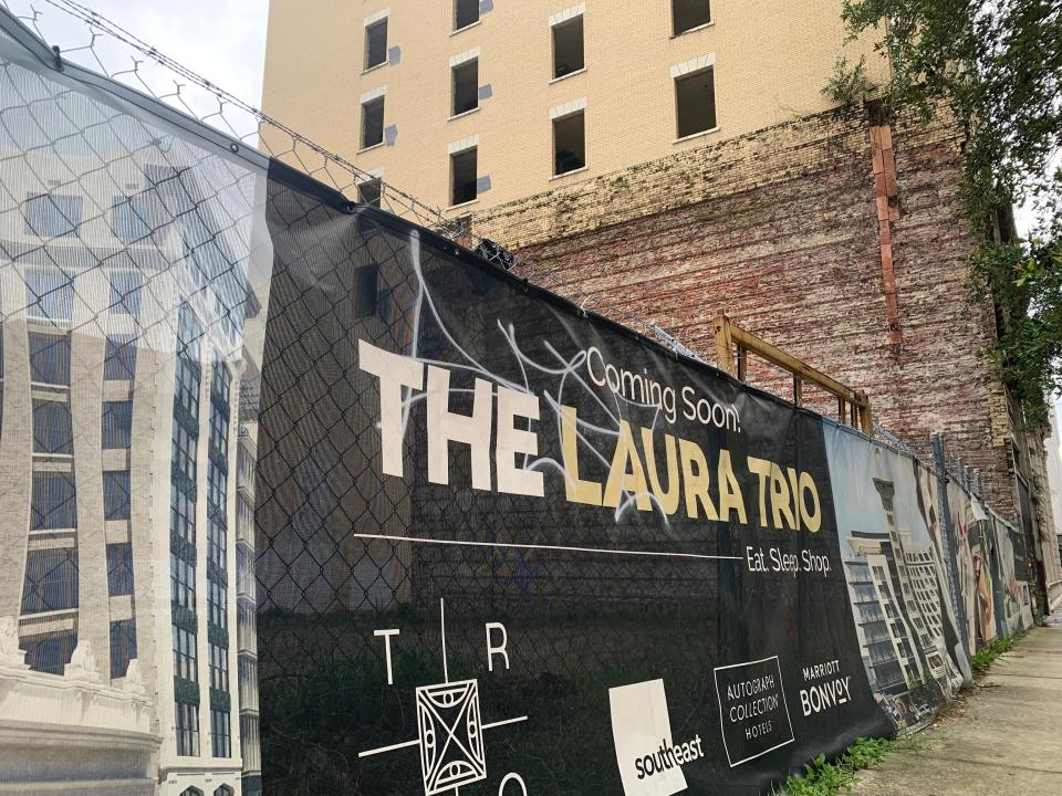 A "Coming Soon" sign hanging on a fence beside a Laura Street sidewalk has been the most visible sign of any activity on the Laura Street Trio since Jacksonville City Council approved a redevelopment agreement in September 2021. City Council will consider approving a new path forward for restoration of the historic buildings.